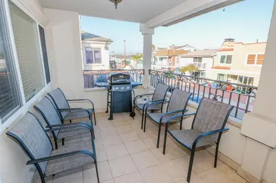 a patio with chairs and a grill on a balcony at 7Br Retreat, Oceanview Balcony And Patio, Steps From Sand By Beachview Rentals in Newport Beach