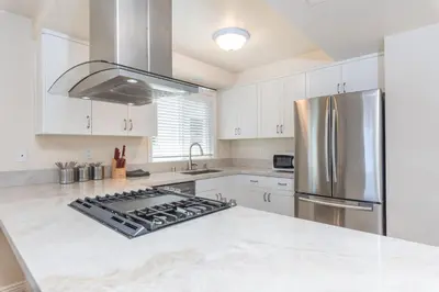 a kitchen with white cabinets and a stainless steel refrigerator at 7Br Retreat, Oceanview Balcony And Patio, Steps From Sand By Beachview Rentals in Newport Beach