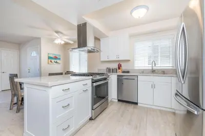 a kitchen with white cabinets and a stainless steel refrigerator at 7Br Retreat, Oceanview Balcony And Patio, Steps From Sand By Beachview Rentals in Newport Beach
