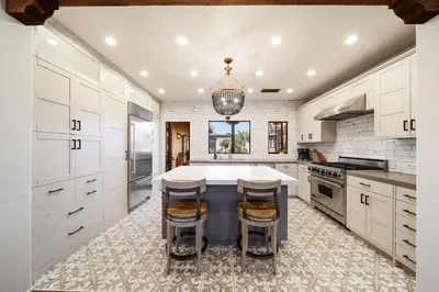 a kitchen with white cabinets and a table with stools at Oceanview Rooftop Escape Modern Spanish Decor in San Diego