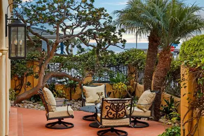 a patio with chairs and palm trees and the ocean at Majestic Corner Coastal Haven in San Diego