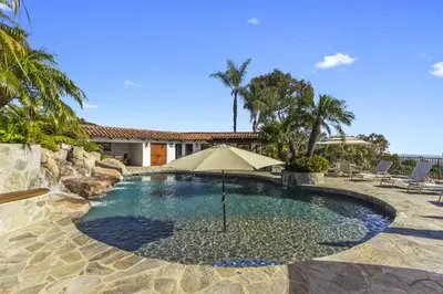 a swimming pool with an umbrella and some chairs at North County Oasis in Vista