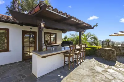 an outdoor kitchen with a bar with stools at North County Oasis in Vista