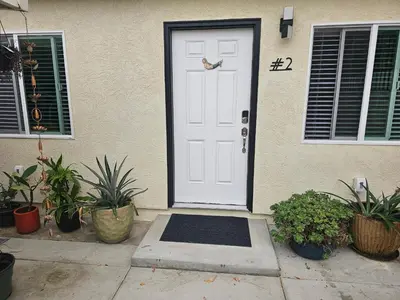 a white door of a house with plants at Beautiful new construction 1br with full size appliances centrally located in La Mesa