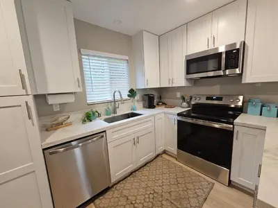 a kitchen with white cabinets and stainless steel appliances at Beautiful new construction 1br with full size appliances centrally located in La Mesa