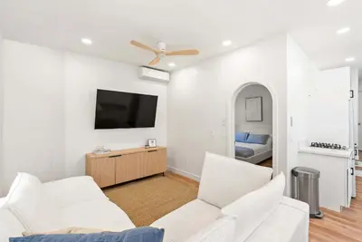 a living room with two white chairs and a flat screen tv at La Jolla Villa by the Sea - Walk to Windansea in San Diego