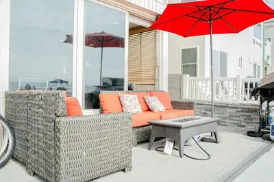 a patio with a couch and a table and a red umbrella at Ocean Front On Beach! -2 Master BR, 2 Full BA, Patio!, AC, Parking, Close to All in San Diego