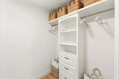 a walk in closet with white cabinets and baskets at Luxury La Jolla Beach Retreat - Steps to Windansea in San Diego