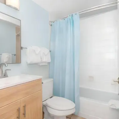 a bathroom with a toilet and a blue shower curtain at Newport Beach Oceanside Stay in Newport Beach