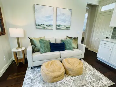 a living room with a couch and a ottoman at Newly Built Coastal Southern California Getaway in Carlsbad