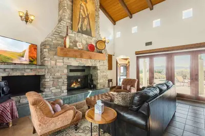 a living room with a stone fireplace and leather furniture at Fallbrook Vineyard Estate in Fallbrook