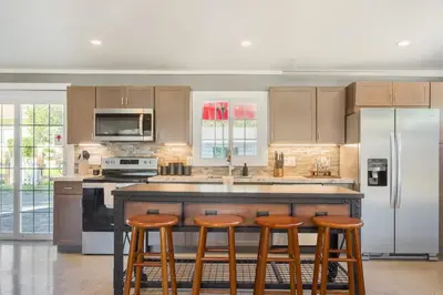 a kitchen with a large island with three bar stools at Man Cave and She Shed in Fallbrook