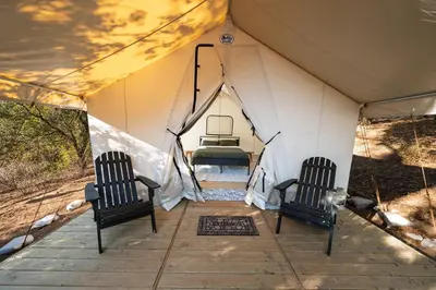 a tent with two chairs and a bed in it at Boutique Nature Retreat in the Palomar Mountains in Pauma Valley