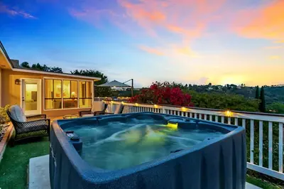 a hot tub on a balcony with a sunset at Newly Furnished 3BR 1BA - Spa - AC - Large Backyard in San Diego