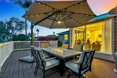 a wooden deck with a table and chairs and an umbrella at Newly Furnished 3BR 1BA - Spa - AC - Large Backyard in San Diego