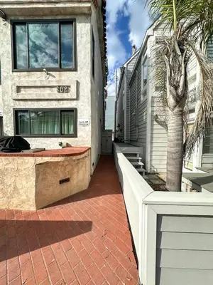 a house with a palm tree next to a building at Mission Beach Loft Garage Steps 2 Ocean in San Diego
