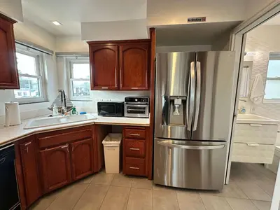 a kitchen with a stainless steel refrigerator and wooden cabinets at Entire Mission Beach Duplex Steps 2 the Ocean & Bay 2 Parking Spots in San Diego