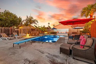a swimming pool with chairs and a red umbrella at Stay & Play Pacific Beach Compound in San Diego