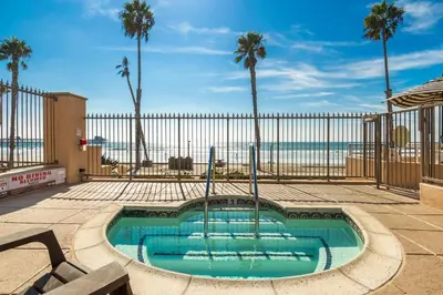 a swimming pool with a fence and palm trees at 5N-31 Beach View BBQ & Jacuzzi in Oceanside