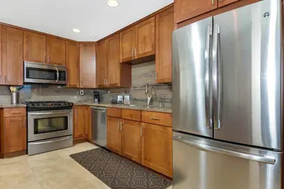 a kitchen with wooden cabinets and a stainless steel refrigerator at 5N-53 Beach Bliss Ocean Views in Oceanside