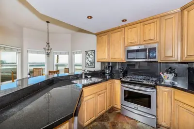a kitchen with wooden cabinets and stainless steel appliances at 5N-64 Beachfront On the Strand in Oceanside