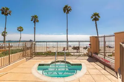 a swimming pool with palm trees and the beach at 5N-64 Beachfront On the Strand in Oceanside
