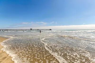 a beach with waves and a pier in the ocean at 5N-64 Beachfront On the Strand in Oceanside
