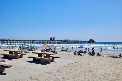a group of people on a beach with a pier at 501P-12 Spectacular Ocean Views Pet Friendly in Oceanside