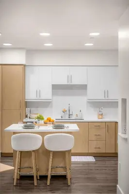 a kitchen with white cabinets and a counter with two stools at Luxury 1BR Newport Beach Condo with Pool and Gym in Newport Beach