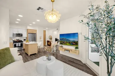 a living room with a white couch and a kitchen at Luxury 1BR Newport Beach Condo with Pool and Gym in Newport Beach