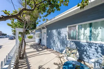a blue house with a tree next to a sidewalk at Suite Cozy Beach Nook 150 Steps To The Sand in San Diego