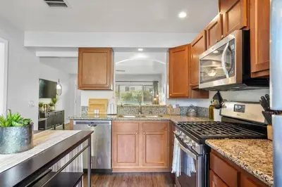 a kitchen with wooden cabinets and stainless steel appliances at Inviting 2-BR Condo in the heart of Imperial Beach in Imperial Beach