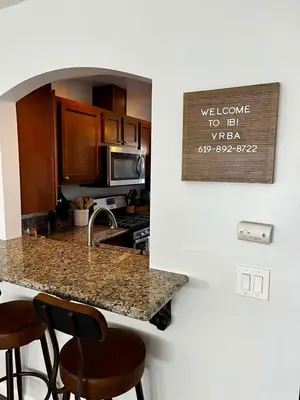 a kitchen with a counter with stools around it at Inviting 2-BR Condo in the heart of Imperial Beach in Imperial Beach