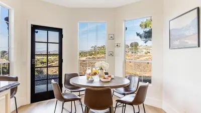 a dining room with a table and chairs and windows at Temecula Stay w Pool Movie Room Sauna Tennis Court Panoramic Valley Views Via de Oro Estate by Avantstay in Temecula