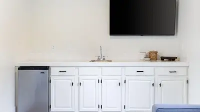 a white kitchen with a sink and a tv on the wall at Temecula Stay w Pool Movie Room Sauna Tennis Court Panoramic Valley Views Via de Oro Estate by Avantstay in Temecula