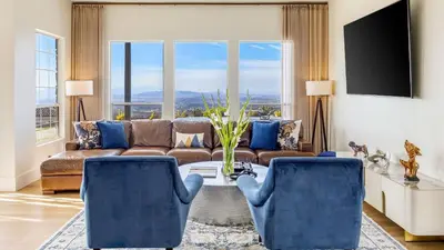 a living room with a couch and blue chairs at Temecula Stay w Pool Movie Room Sauna Tennis Court Panoramic Valley Views Via de Oro Estate by Avantstay in Temecula