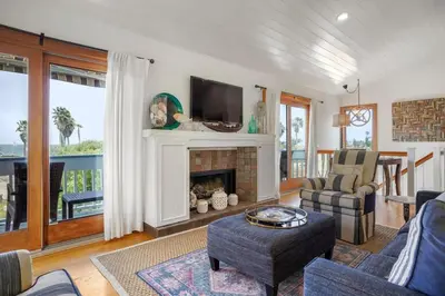 a living room with a fireplace and a tv at Darling Del Mar Beach Cottage with Ocean Views in San Diego