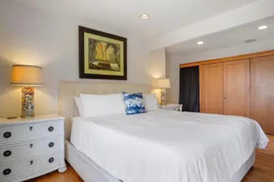 a bedroom with a white bed and a dresser at Darling Del Mar Beach Cottage with Ocean Views in San Diego
