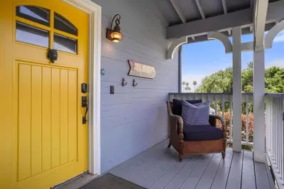 a yellow door on a porch with a chair at Darling Del Mar Beach Cottage with Ocean Views in San Diego
