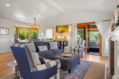a living room with a blue couch and chairs at Darling Del Mar Beach Cottage with Ocean Views in San Diego