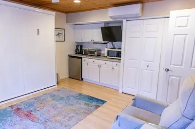 a kitchen with white cabinets and a blue chair at Mission Bay Studio w Ocean Views from Rooftop Deck in San Diego