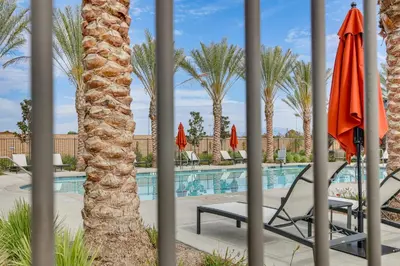 a palm tree with a chair and umbrella next to a swimming pool at Near Hospitals Home with Pool Access in Temecula in Temecula