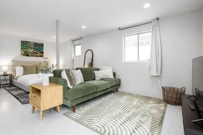 a living room with a green couch and a bed at Brand New Studio in Carlsbad in Carlsbad