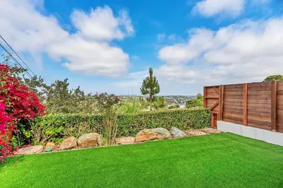 a backyard with a green lawn and a wooden fence at Designer Canyon House in La Jolla in San Diego
