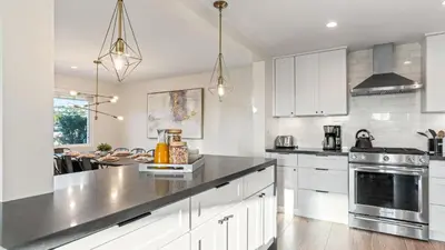a kitchen with white cabinets and a black counter top at Steps to the Beach Modern 3BDR w Patio 257 Trailhead Trestles 1 by AvantStay in San Clemente