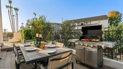 a patio with a grill and a table on a balcony at 2 Condos Steps to the Beach Hot Tub Trestles Trailhead Duo by AvantStay in San Clemente