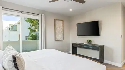 a bedroom with a bed and a flat screen tv at 2 Condos Steps to the Beach Hot Tub Trestles Trailhead Duo by AvantStay in San Clemente