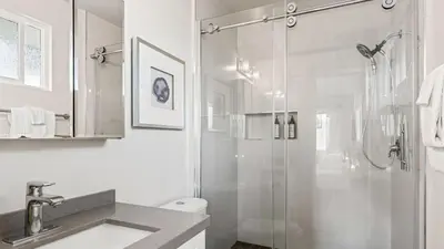 a white bathroom with a shower and a sink at 2 Condos Steps to the Beach Hot Tub Trestles Trailhead Duo by AvantStay in San Clemente