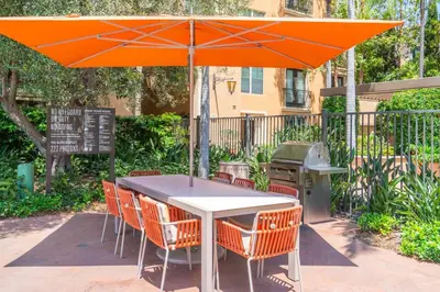 an orange umbrella over a table with chairs and a grill at Modern 2BR Cozy Apartment in Irvine in Lake Forest