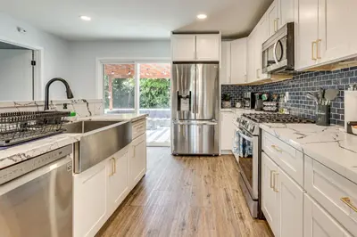 a kitchen with white cabinets and a stainless steel refrigerator at 4 Mi to Dtwn Oceanside and Beach Home with Yard! in Oceanside